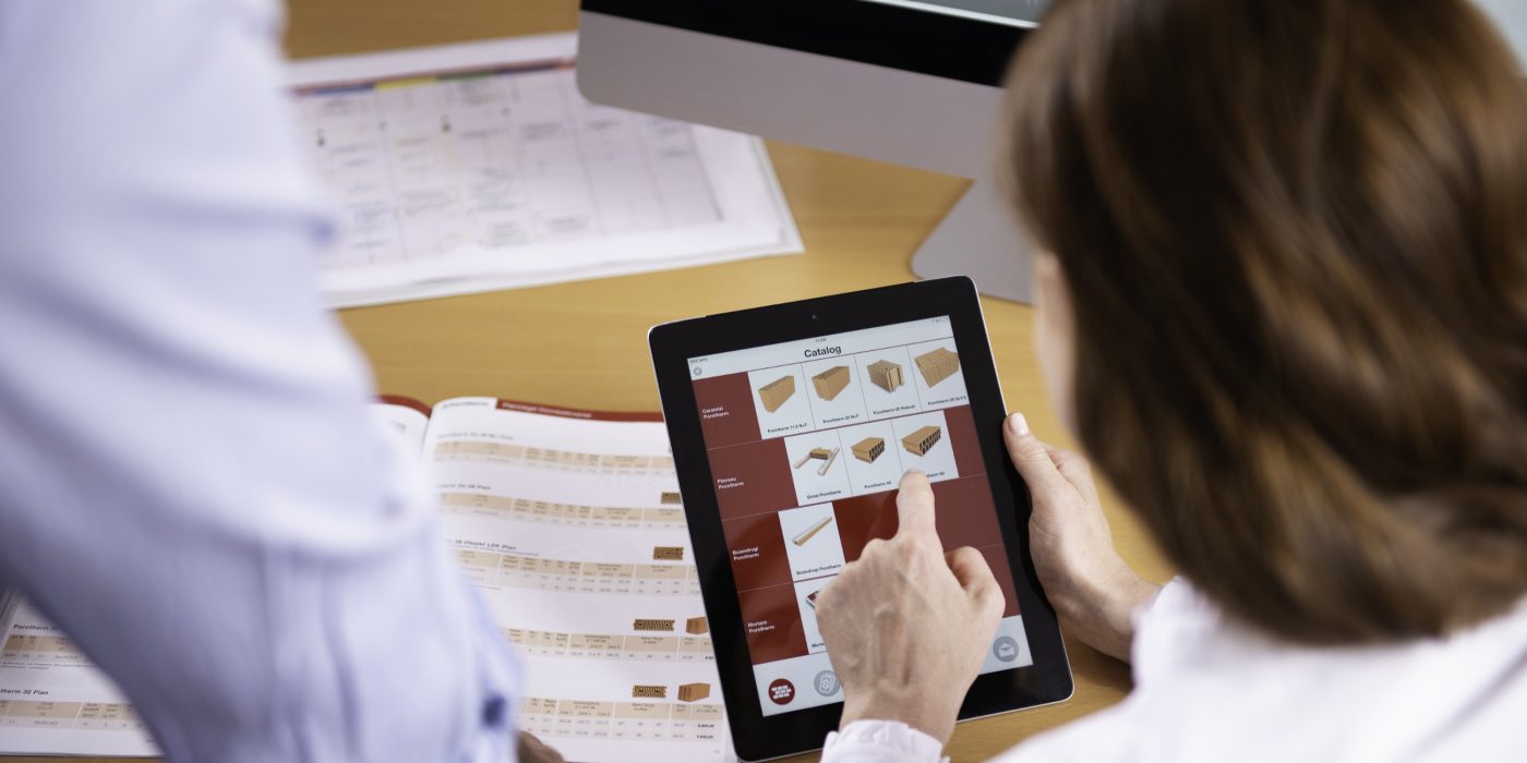 Woman at workplace holding tablet computer sitting next to standing man