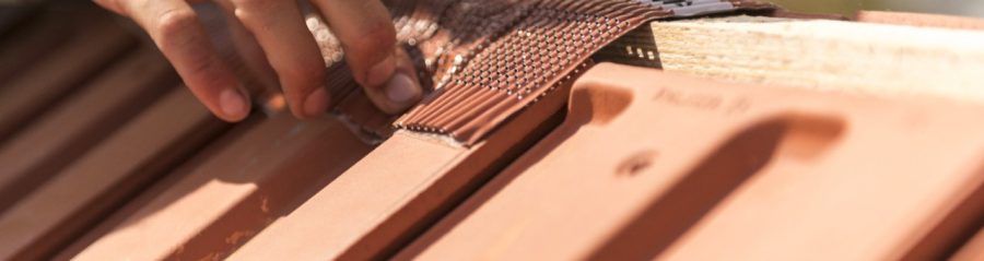 Roofer applying Alu-Grip Rol ridge and hip roll on ridge with bare hands
