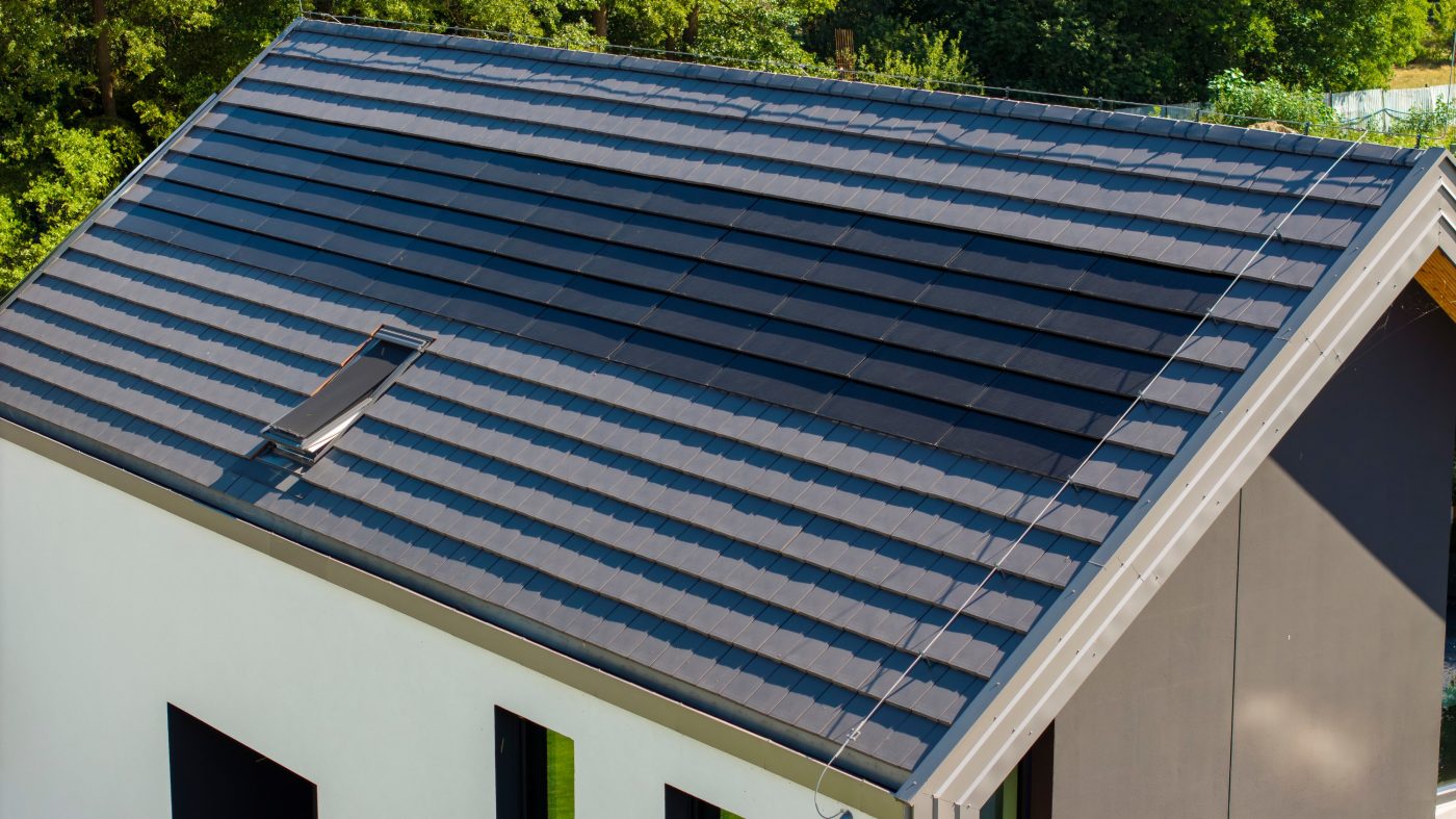 Dom z panelami fotowoltaiczynymi Wevolt X-Tile w kolorze czarnym i płaską dachówką ceramiczną Orea 9 w kolorze szarej angoby
