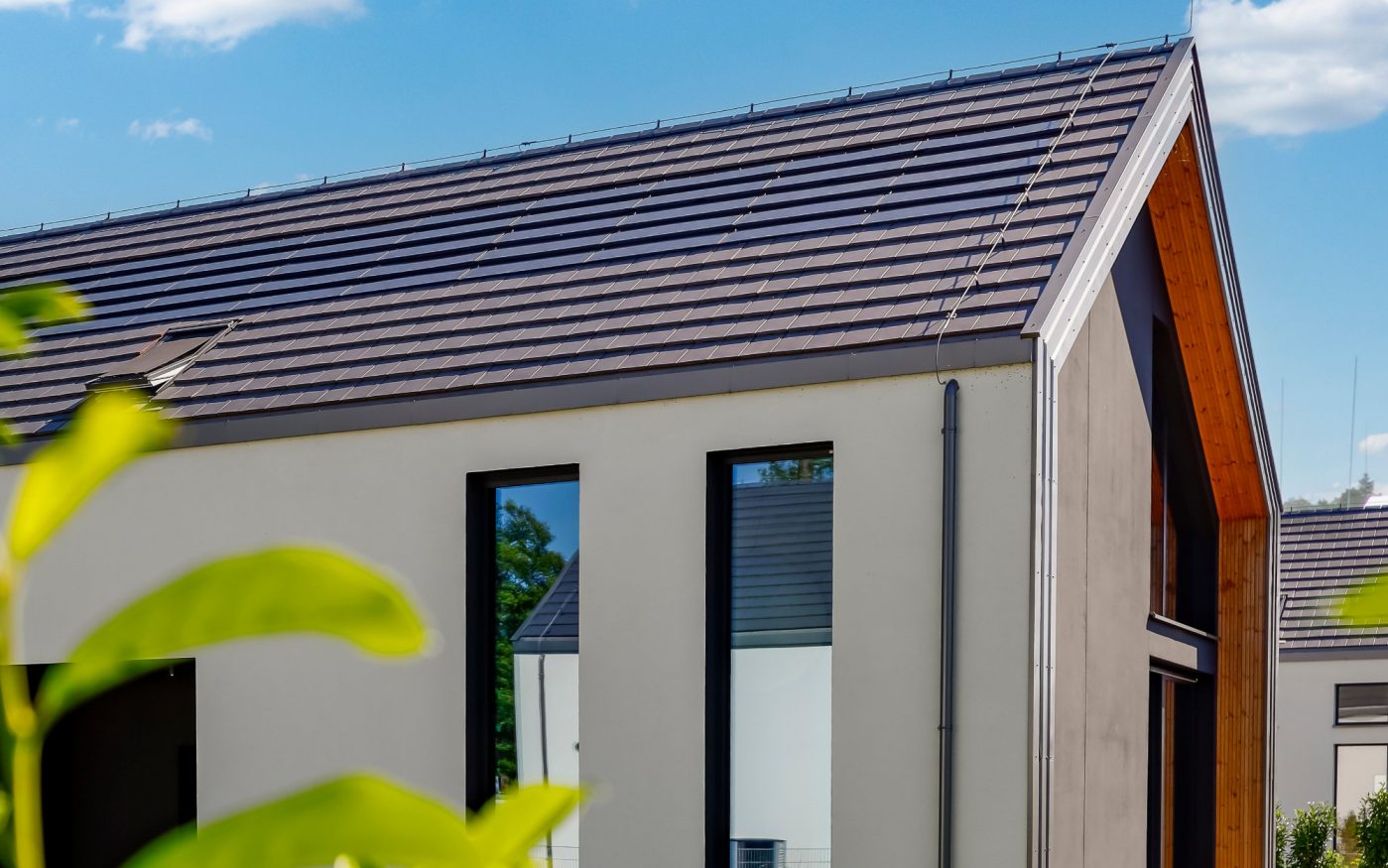 Dom z panelami fotowoltaiczynymi Wevolt X-Tile w kolorze czarnym i płaską dachówką ceramiczną Orea 9 w kolorze szarej angoby