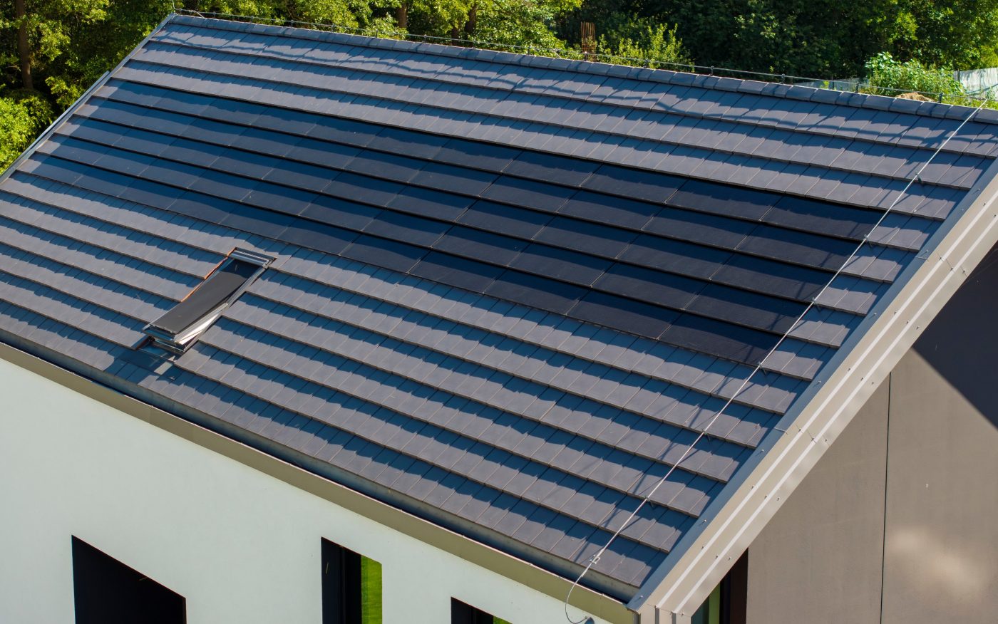 Dom z panelami fotowoltaiczynymi Wevolt X-Tile w kolorze czarnym i płaską dachówką ceramiczną Orea 9 w kolorze szarej angoby