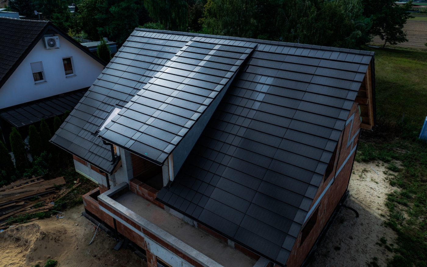 Dom jednorodzinny w Mechnicach z panelami fotowoltaicznymi Wevolt X-Tile w kolorze czarnym i płaską dachówką ceramiczną Orea 9 antarcytowej matowej angoby