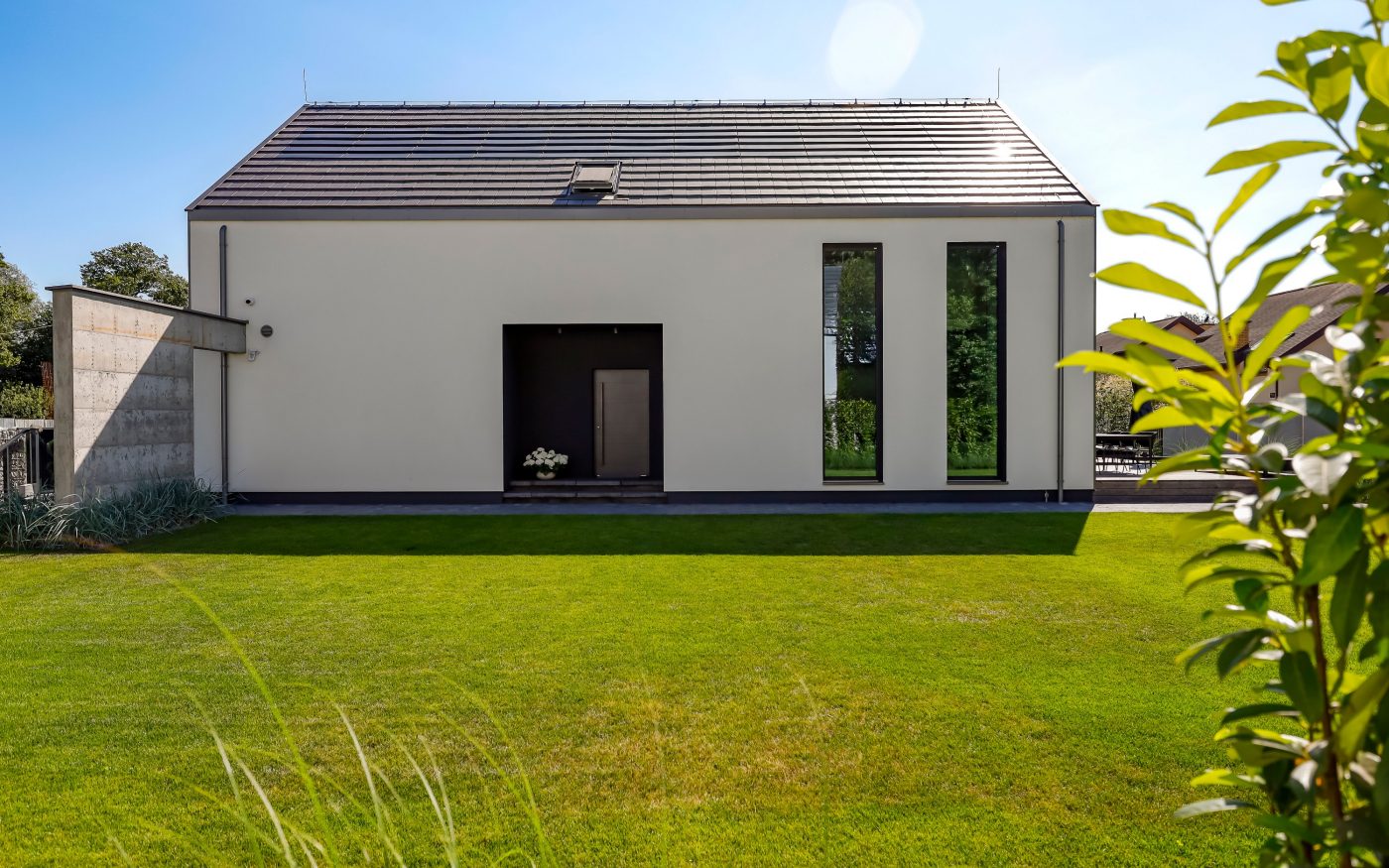 Dom z panelami fotowoltaiczynymi Wevolt X-Tile w kolorze czarnym i płaską dachówką ceramiczną Orea 9 w kolorze szarej angoby