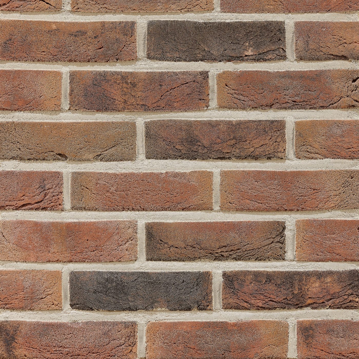 Tekstura cegieł i płytek klinkierowych Terca Kasztan. Powierzchnia lica jest ręcznie formowana i charakteryzuje się odcieniami czerwieni, brązu oraz czerni.